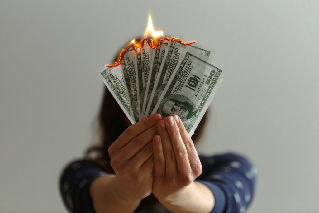 photo of woman holding money that's burning meant to represent wasting on bad link building