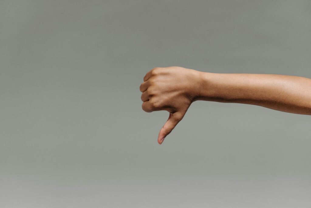 Close-up of a person's hand giving a thumbs down gesture representing bad link building